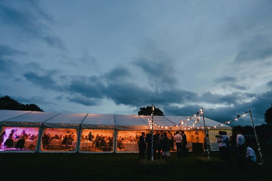 Elegant outdoor dinner party with string lights inside a marquee tent
